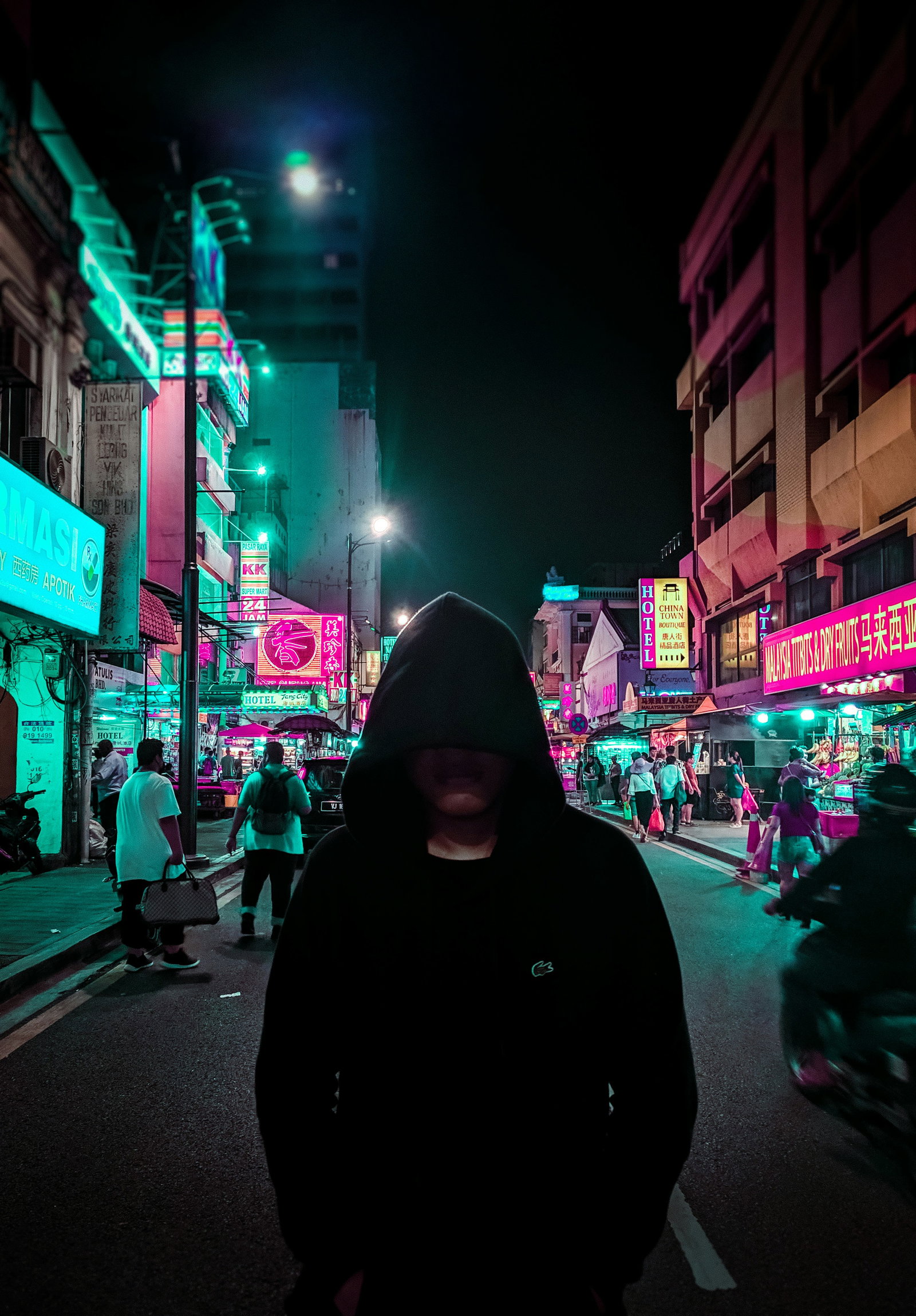 man in black hoodie walking on street during night time